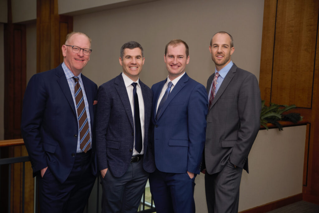 The four surgeons at Midwest Center for Joint Replacement standing in a line and smiling.