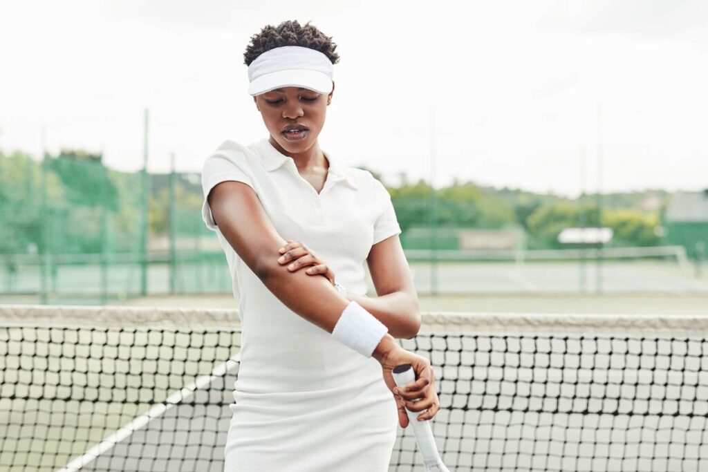 A photo of a female tennis player holder her elbow in pain