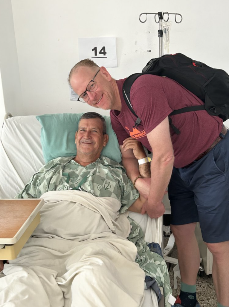 Dr. Berend sitting with a male patient in hospital bed in Guatemala